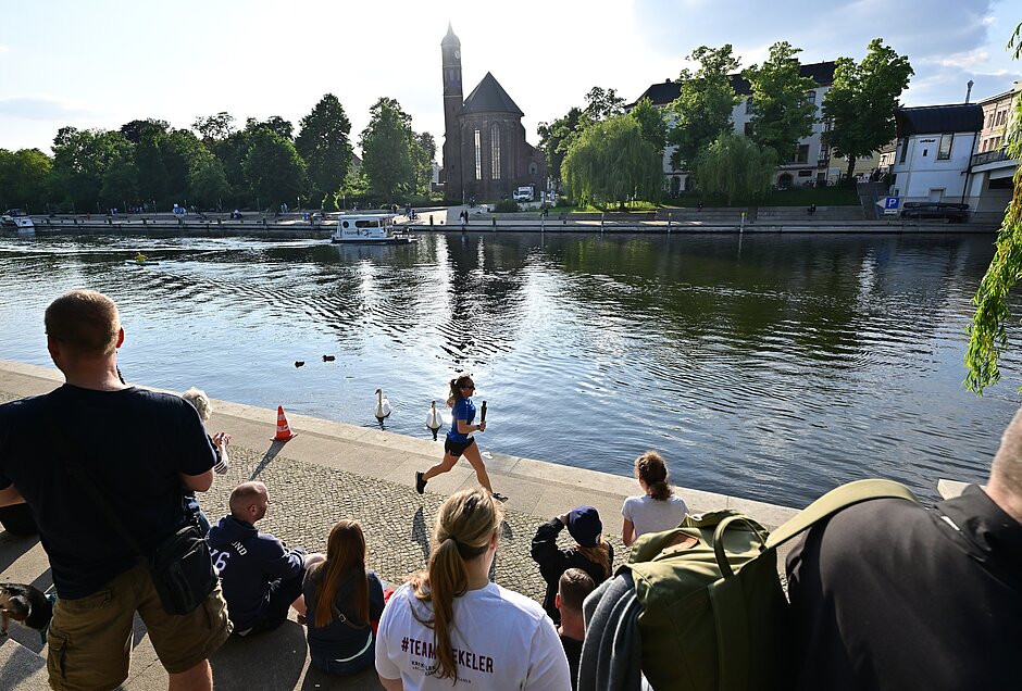 Team Staffel Brandenburg: Läuferin an der Promenade der Niederhavel passiert Zuschauer @ SCC EVENTS / Petko Beier