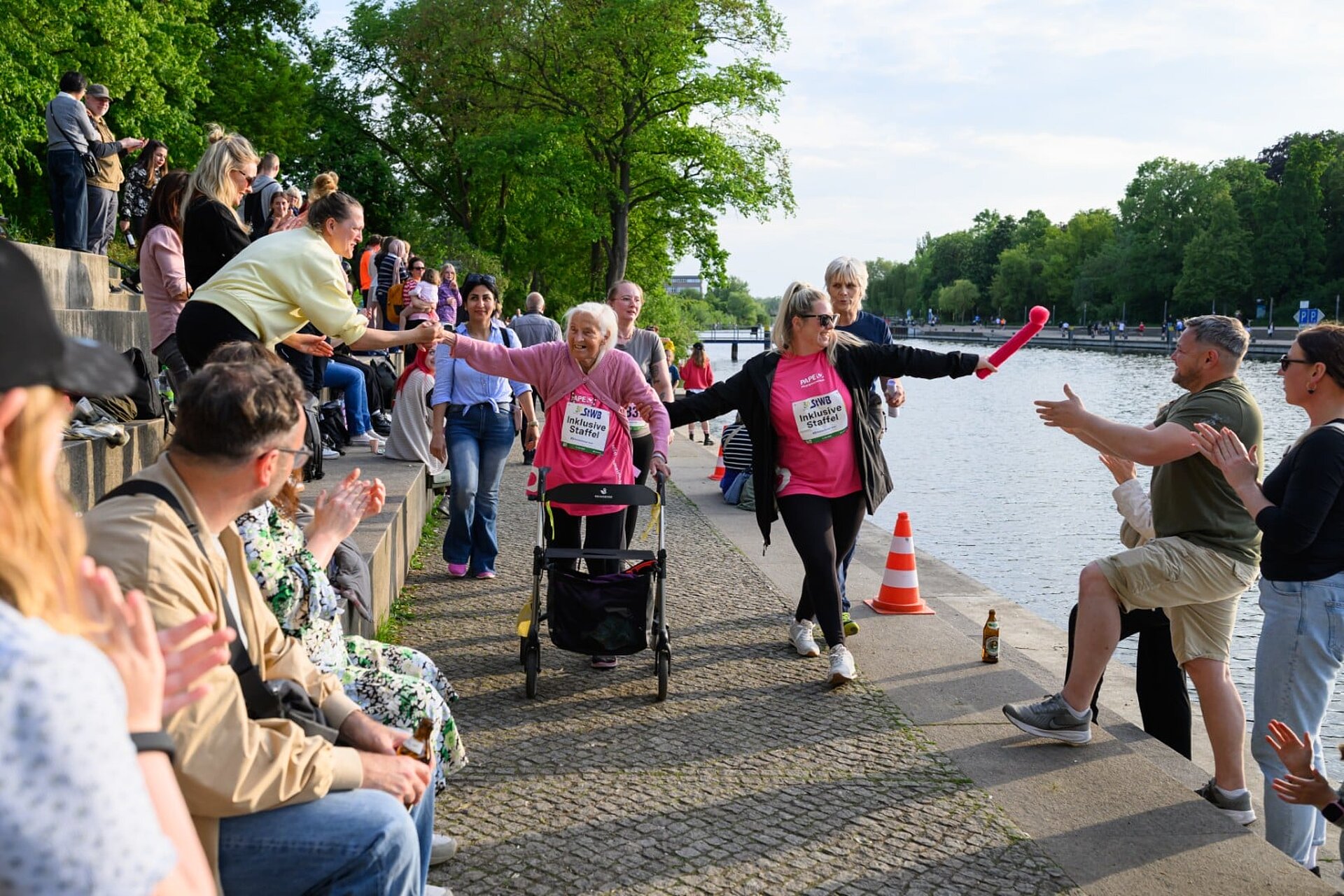 Teilnehmende Rentnerin mit Rollator und ihre Begleiterin werden angefeuert während sie an der Havel entlanglaufen.