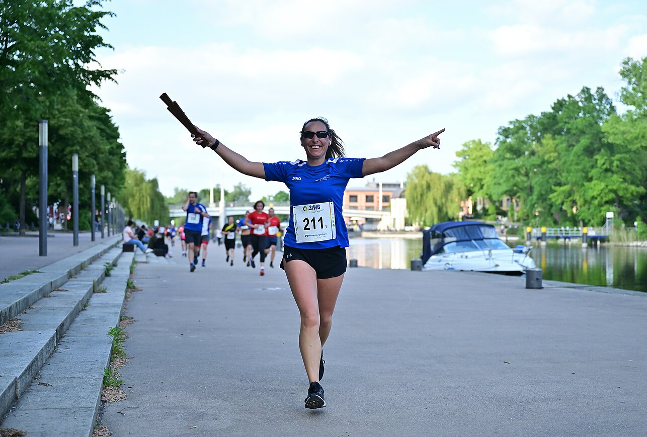 Eine laufende Frau nimmt ihre Arme hoch und freut sich ©SCC EVENTS / Petko Beier 