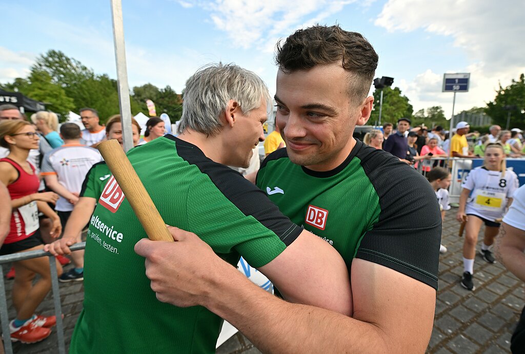 Team Staffel Brandenburg Fotos (2023): Zwei männliche Läufer umarmen sich bei der Übergabe des Staffelstabs @ SCC EVENTS / Petko Beier 