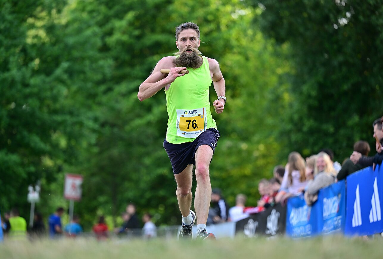 Ein Läufer mit Bart läuft über eine Wiese ©SCC EVENTS / Petko Beier 
